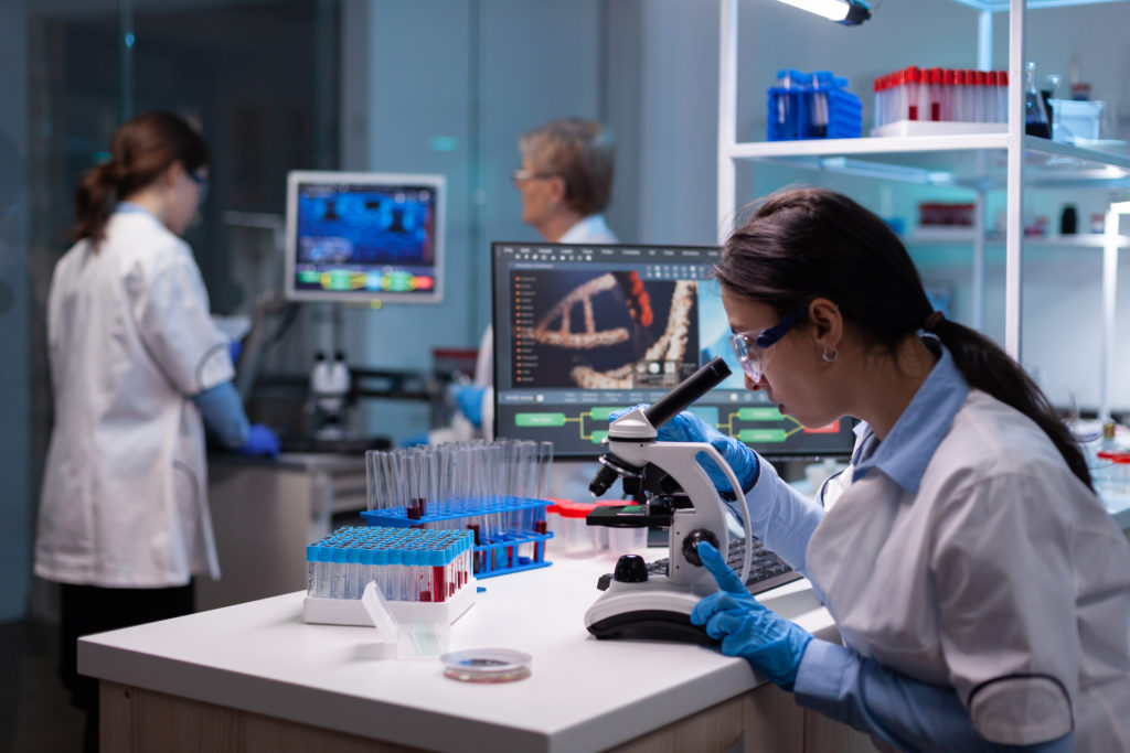 Biochemist scientists studying reaction of virus on microscope in laboratory